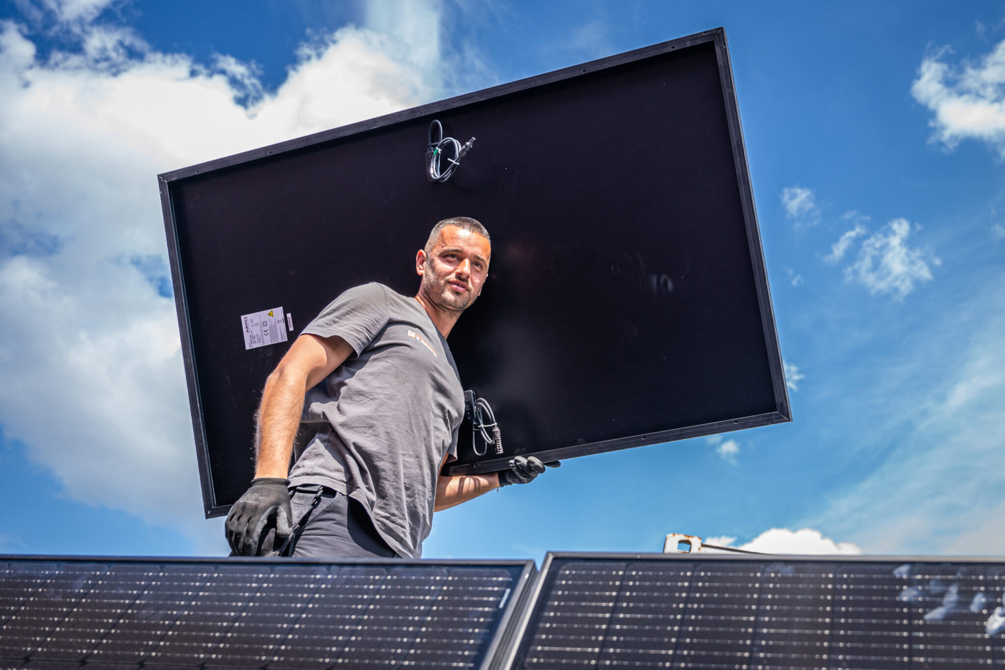 Mitarbeiter auf dem Dach mit einem Solarpanel